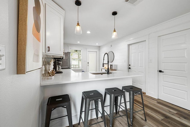 65 Brown St, Santa Rosa Beach, FL 32459 - kitchen with a sink, a peninsula, white cabinets, wood finished floors, and a kitchen bar