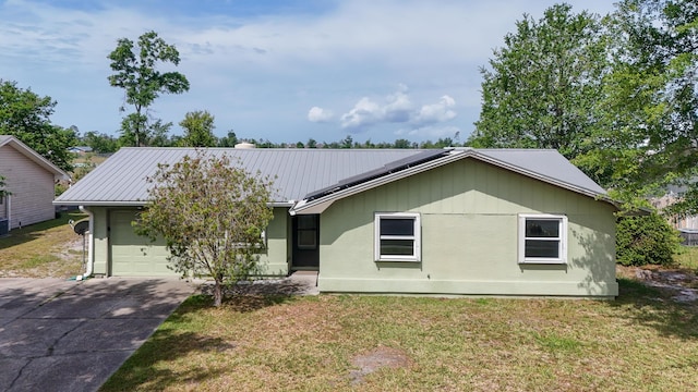 single story home with a garage, driveway, a front yard, and metal roof