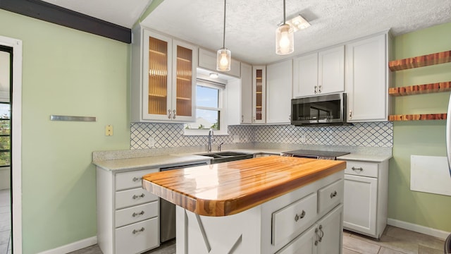kitchen featuring stainless steel microwave, a sink, tasteful backsplash, and baseboards