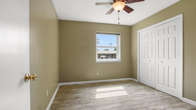unfurnished bedroom featuring wood finished floors, a closet, baseboards, and a ceiling fan