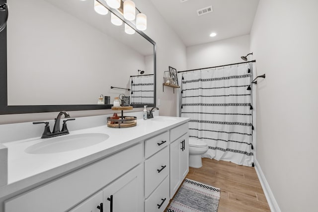 bathroom featuring toilet, wood finished floors, double vanity, recessed lighting, and a shower with curtain