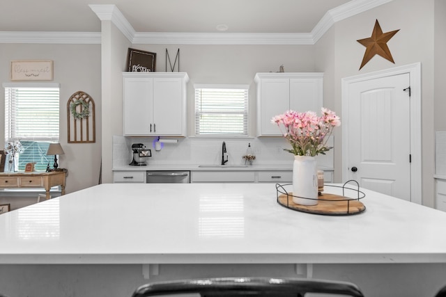 kitchen with a sink, dishwasher, backsplash, crown molding, and light countertops