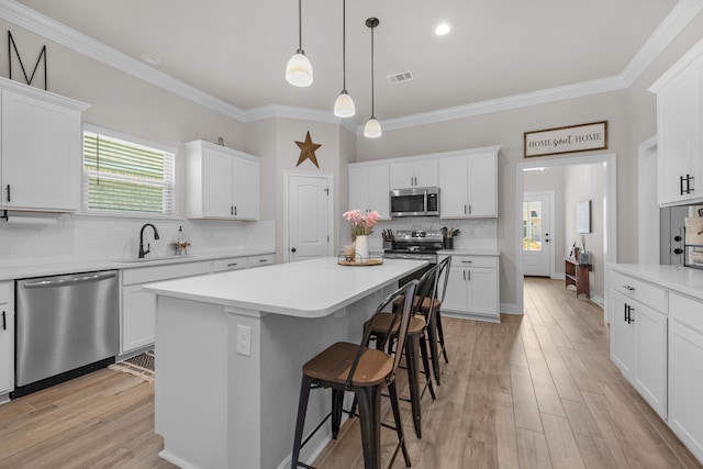 kitchen featuring stainless steel appliances, a sink, a breakfast bar area, backsplash, and crown molding