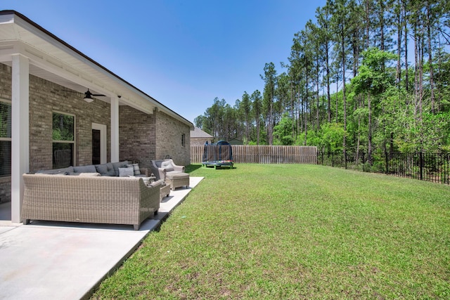 view of yard featuring an outdoor living space, ceiling fan, a trampoline, and a patio