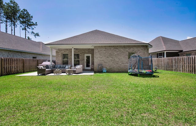 rear view of property with an outdoor hangout area, a trampoline, a patio area, brick siding, and a shingled roof