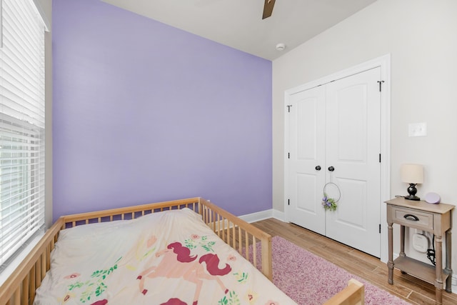 bedroom with wood finished floors, a closet, baseboards, and ceiling fan