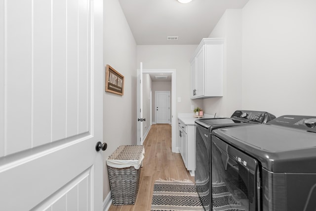 washroom featuring cabinet space, light wood-type flooring, separate washer and dryer, and baseboards