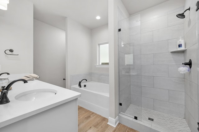 full bath with wood finished floors, a garden tub, a stall shower, recessed lighting, and double vanity