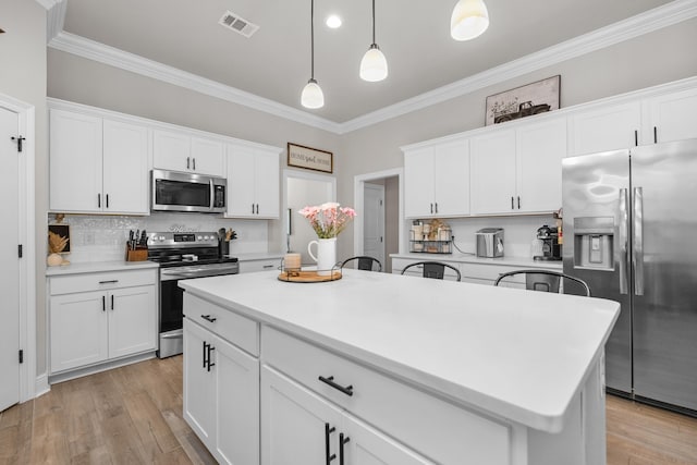 kitchen with appliances with stainless steel finishes, crown molding, white cabinetry, backsplash, and pendant lighting