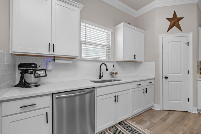 kitchen with stainless steel dishwasher, a sink, ornamental molding, white cabinetry, and tasteful backsplash