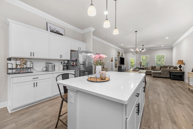 kitchen with stainless steel fridge, light wood-style floors, a kitchen bar, a kitchen island, and white cabinets