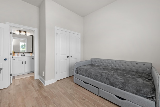 bedroom with a sink, light wood-type flooring, baseboards, and a closet