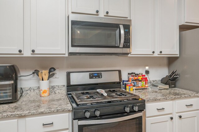 1126 Valor Walk, Crestview, FL 32539 - kitchen with stainless steel appliances, white cabinetry, and light stone counters