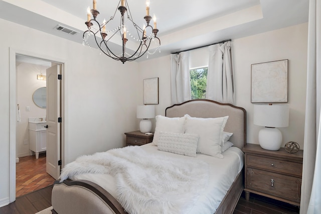 4485 Luke Ave Unit B, Destin, FL 32541 - bedroom featuring dark wood-type flooring, a chandelier, a tray ceiling, baseboards, and ensuite bathroom
