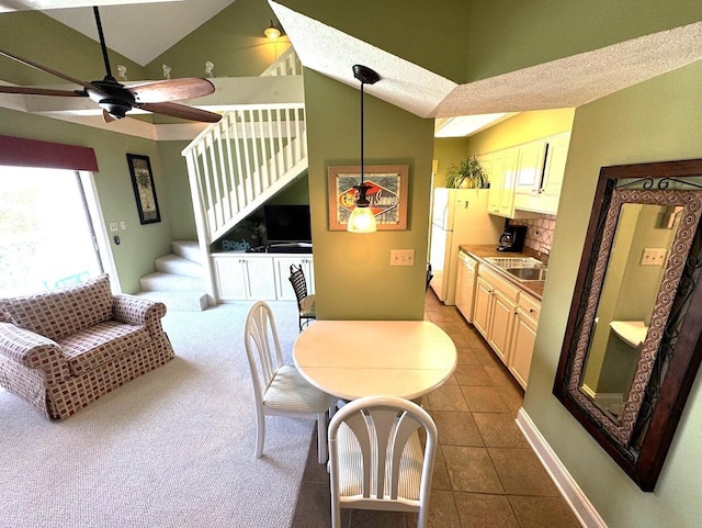 dining room with high vaulted ceiling, stairs, ceiling fan, baseboards, and dark tile patterned floors