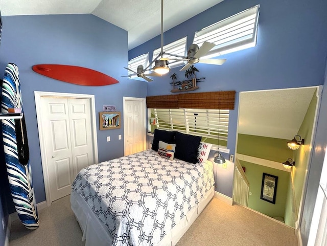bedroom featuring carpet flooring, high vaulted ceiling, baseboards, ceiling fan, and two closets