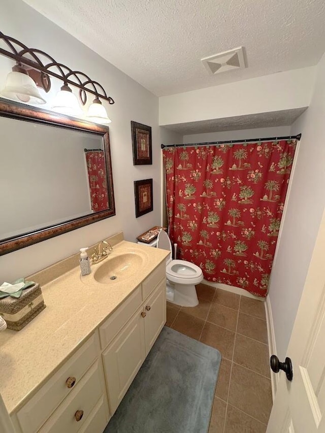 bathroom featuring a textured ceiling, tile patterned floors, vanity, toilet, and baseboards