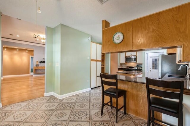 84 12th St, Shalimar, FL 32579 - kitchen with appliances with stainless steel finishes, a peninsula, dark countertops, a sink, and baseboards