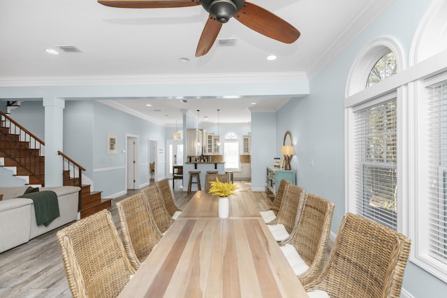 dining area featuring light wood finished floors, stairs, ceiling fan, baseboards, and ornamental molding