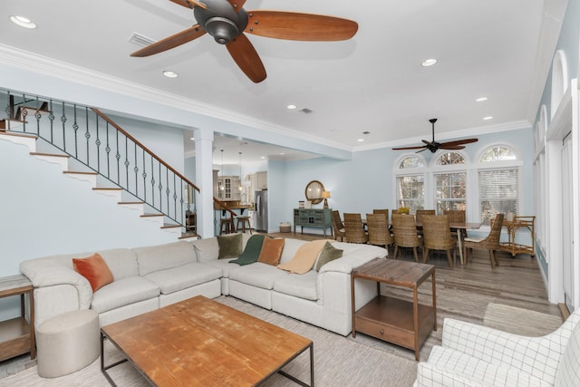 living area featuring ceiling fan, crown molding, wood finished floors, recessed lighting, and stairway