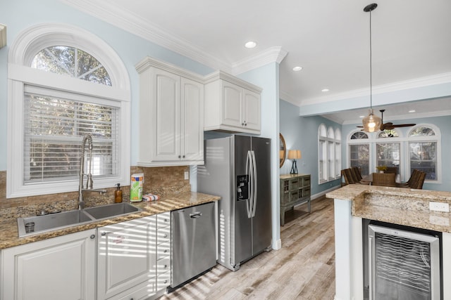 kitchen with wine cooler, a sink, appliances with stainless steel finishes, light wood-style flooring, and decorative backsplash