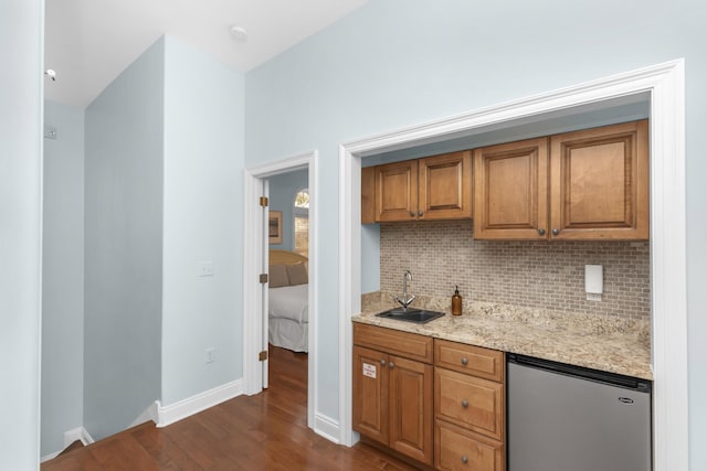 kitchen featuring fridge, dark wood-type flooring, backsplash, and brown cabinetry