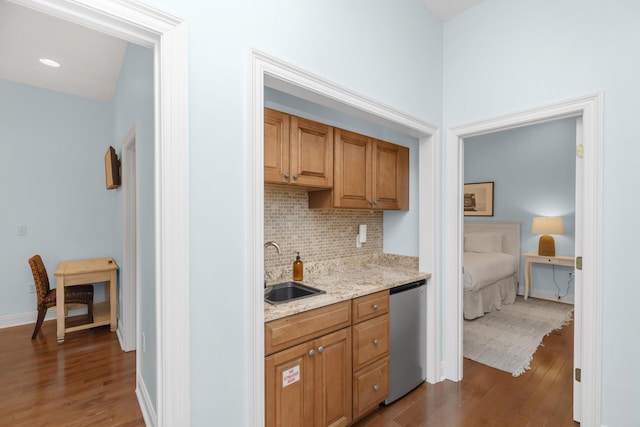 kitchen with a sink, backsplash, dark wood-type flooring, and stainless steel dishwasher