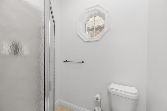 bathroom with toilet, baseboards, tile patterned flooring, and a stall shower