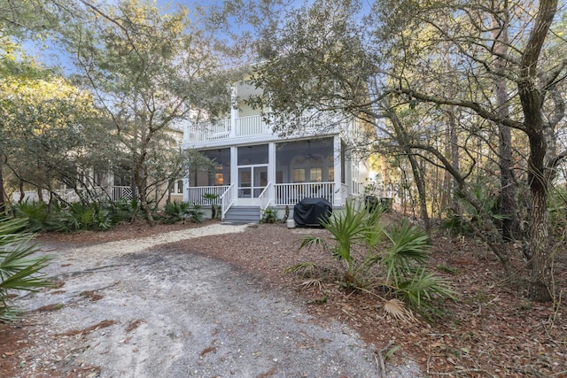 view of front of property featuring a sunroom, ceiling fan, and a balcony