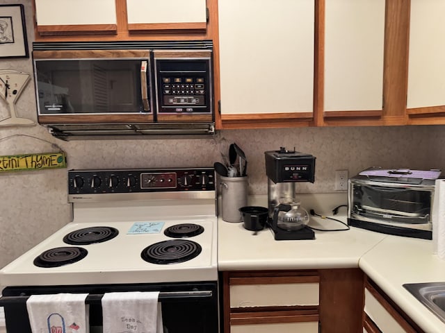 kitchen featuring electric range, black microwave, and light countertops