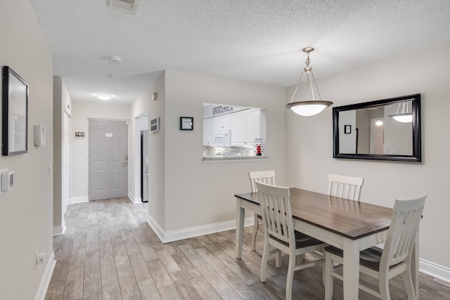 4274 Calinda Ln Unit 215, Niceville, FL 32578 - dining room with light wood-type flooring, baseboards, and a textured ceiling