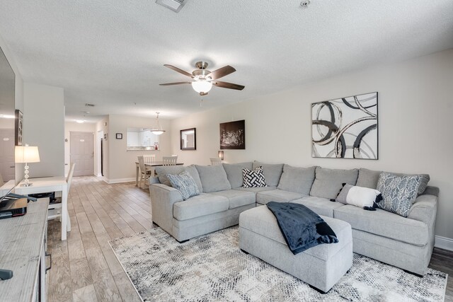 4274 Calinda Ln Unit 215, Niceville, FL 32578 - living room featuring wood finished floors, baseboards, a ceiling fan, and a textured ceiling