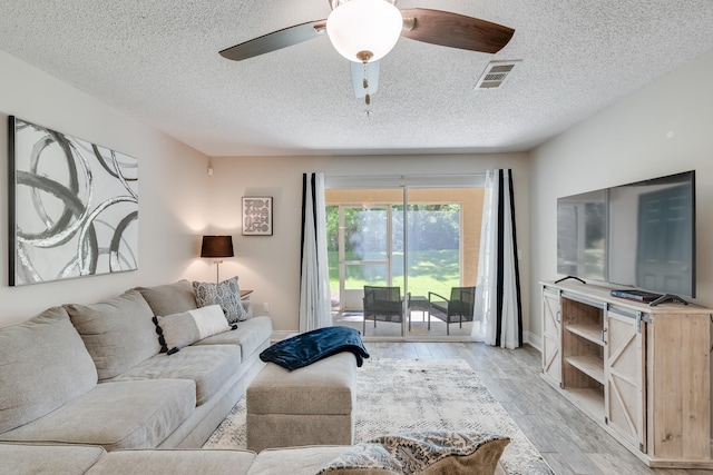 4274 Calinda Ln Unit 215, Niceville, FL 32578 - living room featuring a textured ceiling, light wood-style floors, ceiling fan, and baseboards