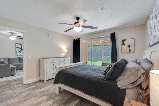 4274 Calinda Ln Unit 215, Niceville, FL 32578 - bedroom with a textured ceiling, light wood-style flooring, ceiling fan, access to outside, and baseboards