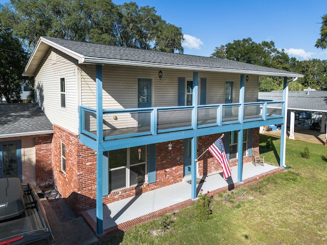 327 NE Yacht Club Dr, Fort Walton Beach, FL 32548 - back of property featuring brick siding, a lawn, a patio area, a balcony, and roof with shingles