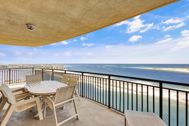 balcony featuring view of water and beach and outdoor dining space