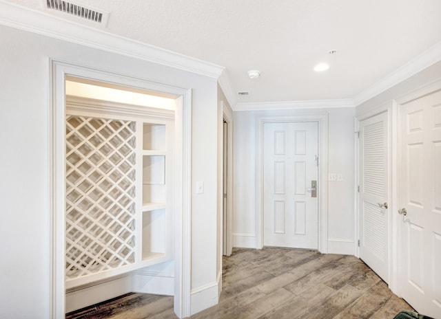 hallway featuring wood finished floors, crown molding, and baseboards