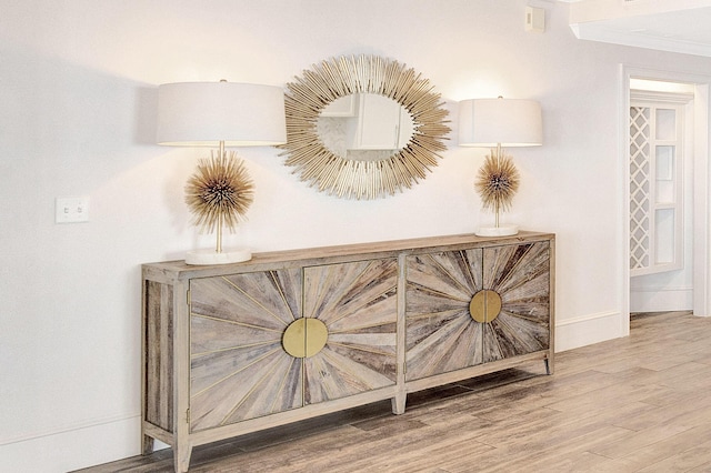 detailed view of wood finished floors, crown molding, and baseboards