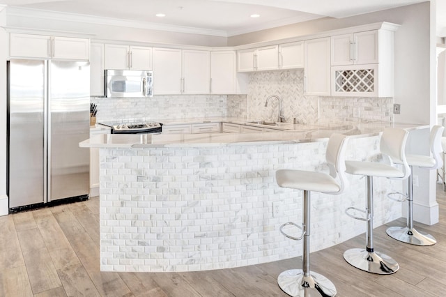kitchen featuring appliances with stainless steel finishes, a sink, light countertops, white cabinets, and ornamental molding