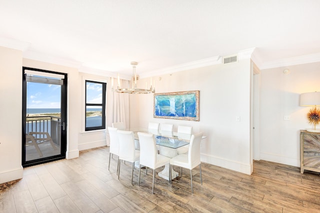 dining space featuring a chandelier, ornamental molding, wood finished floors, and baseboards