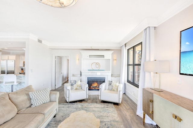 living room with light wood-style flooring, crown molding, a high end fireplace, and baseboards