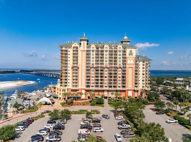 drone / aerial view of a nearby body of water, apartment complex / building, and a notable bridge