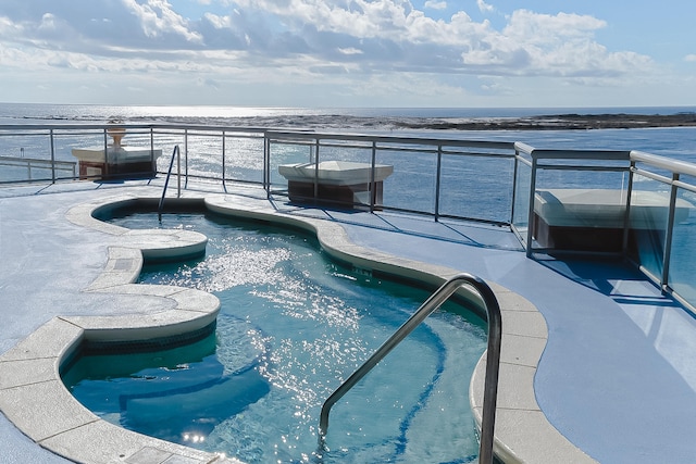 view of swimming pool with a jacuzzi and a water view