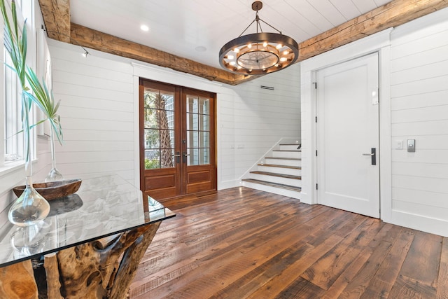 foyer featuring french doors, wood walls, hardwood / wood-style floors, stairway, and a chandelier