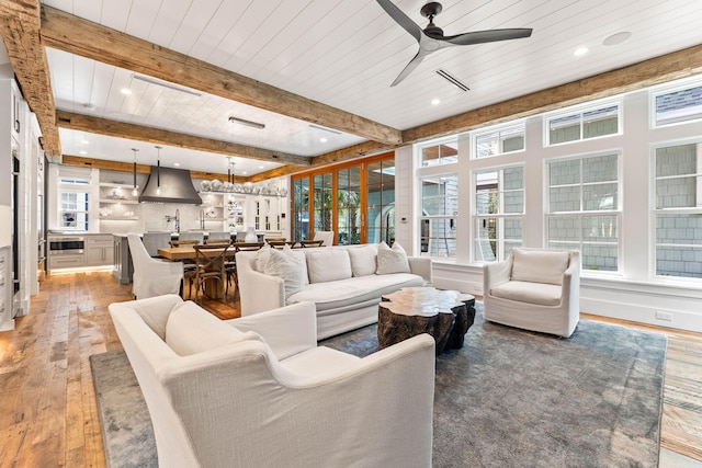 living room featuring light wood-style flooring, recessed lighting, plenty of natural light, ceiling fan, and beamed ceiling