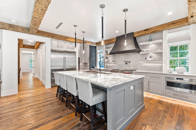 kitchen with a sink, stainless steel appliances, gray cabinetry, light wood finished floors, and open shelves