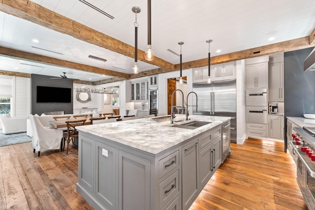 kitchen featuring gray cabinetry, light wood finished floors, beam ceiling, plenty of natural light, and wine cooler