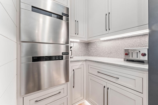 kitchen with decorative backsplash, white cabinets, and light stone countertops