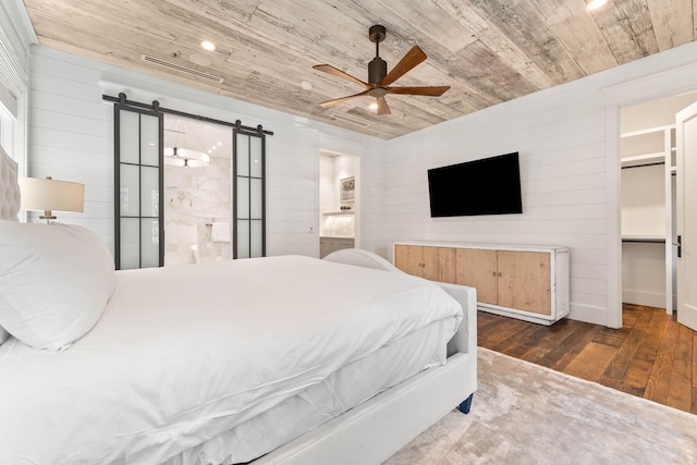 bedroom featuring wood ceiling, a barn door, wood-type flooring, ensuite bathroom, and a ceiling fan