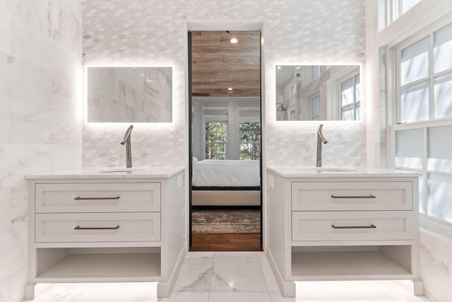 ensuite bathroom featuring marble finish flooring and two vanities